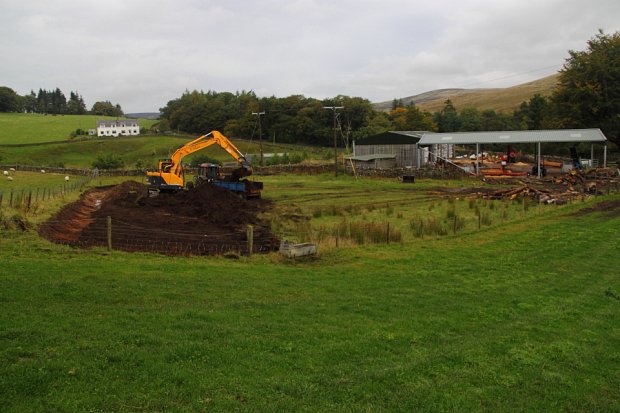 Starting by digging a drain across the top of the yard before lifting the topsoil