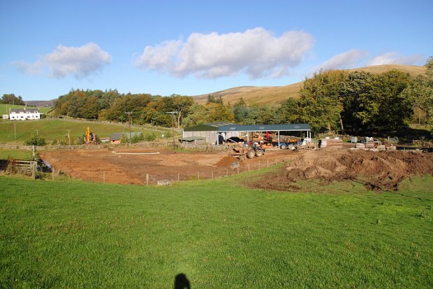 Opening an outlet for the drainage in the background. Large amounts of topsoil heaped to the right